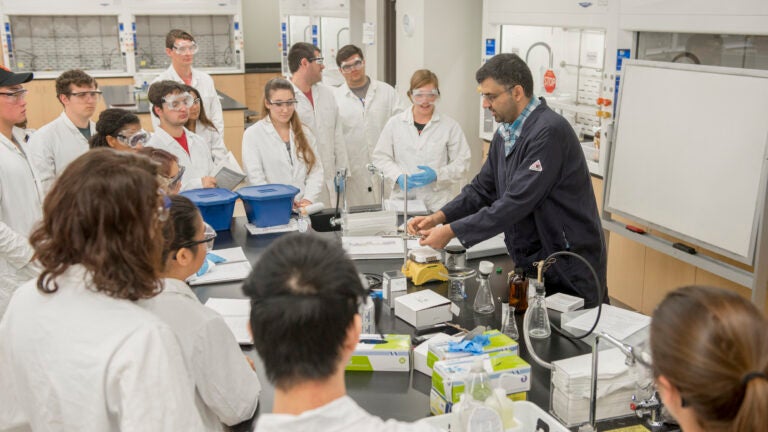 A science professor performing a demonstration for USC students in a laboratory setting.