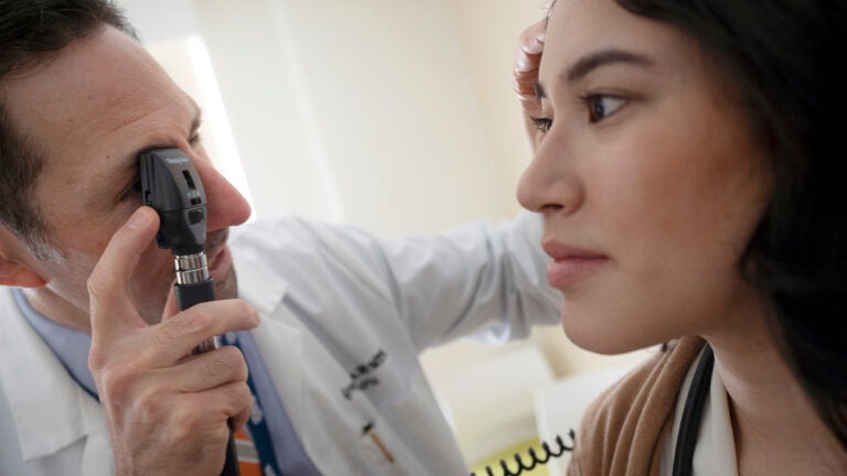 A doctor examining a students eye in a doctor's visit.