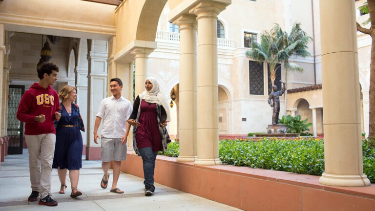 Four students walking through the halls of USC.