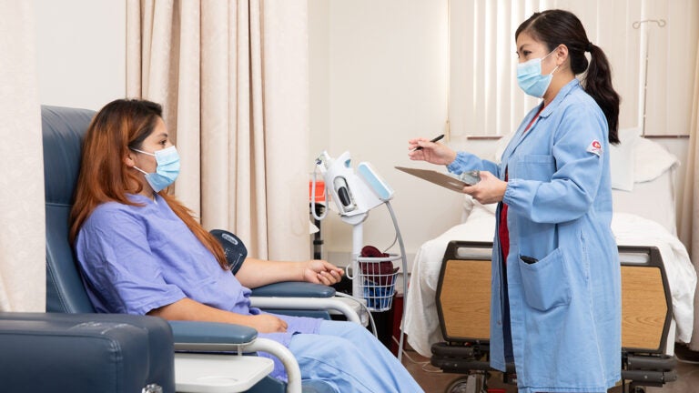 Nurse speaks to patient as they use a machine to check blood pressure.