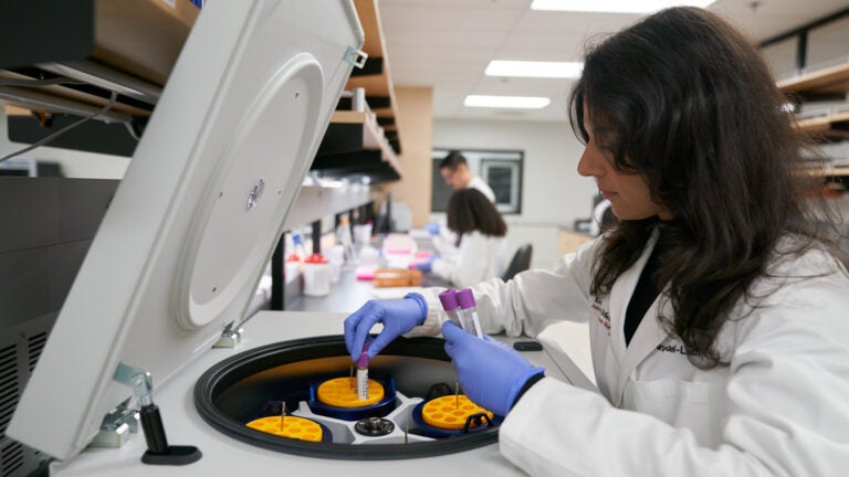 USC researcher from the the Alzheimer’s Therapeutic Research Institute work with vials in front of a machine