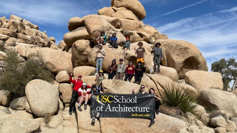 USC School of Architecture students pose for picture in front of a rock formation.