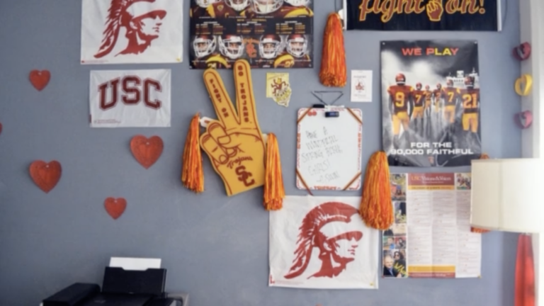 Collection of USC-branded memorabilia pinned to the wall of a dorm bedroom.