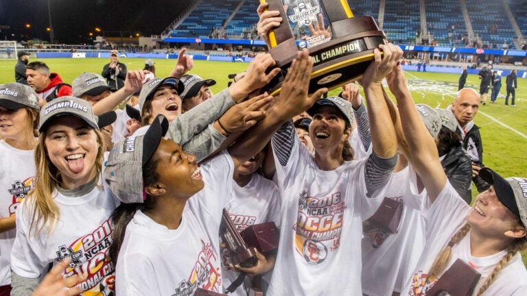 The women’s soccer team celebrating with their trophy.
