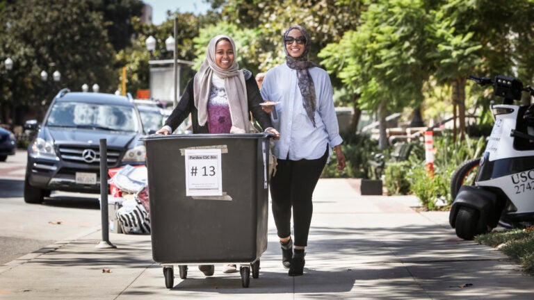 Students roll a cart to load up by Trojan Hall on move-in day