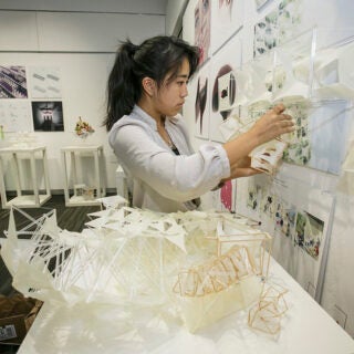 Student adding their architecture model to a presentation wall