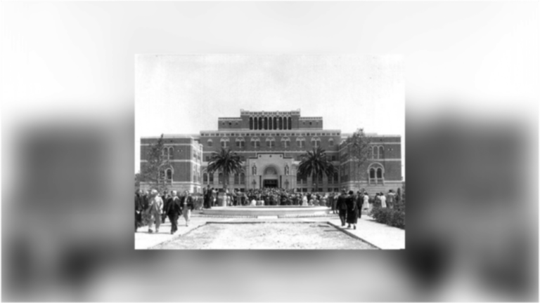 Exterior of the Doheny Library, with palm trees surrounding the majestic brick building