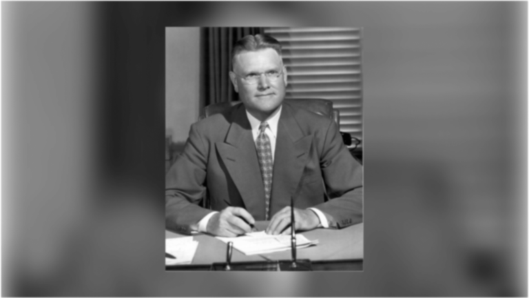USC's sixth president, Fred D. Fagg Jr., sitting at his office in a suit