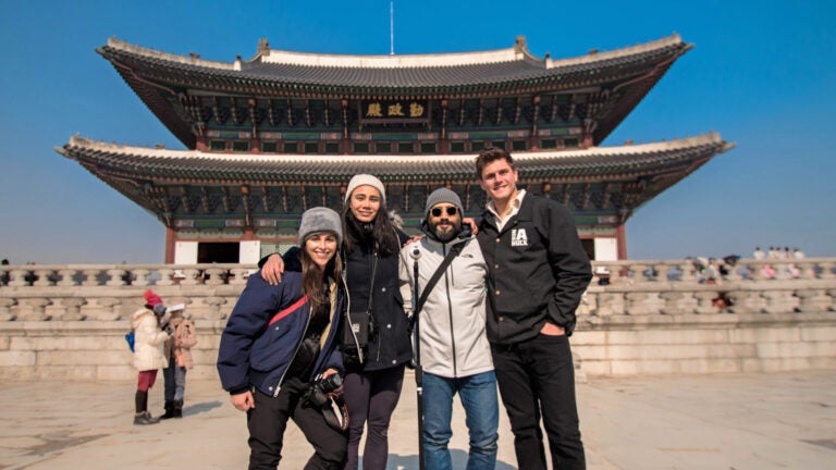 Four USC students pose in front of a monument in PyeongChang during the 2018 Winter Olympics