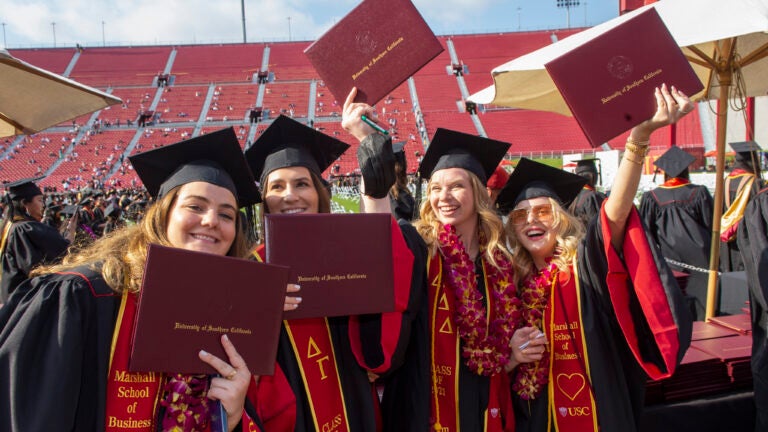Students holding up their diploma at commencement to celebrate their graduation.