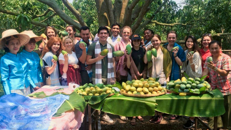 USC Annenberg School for Communication and Journalism students hold mangos and pose for a group photo while on a study abroad trip.