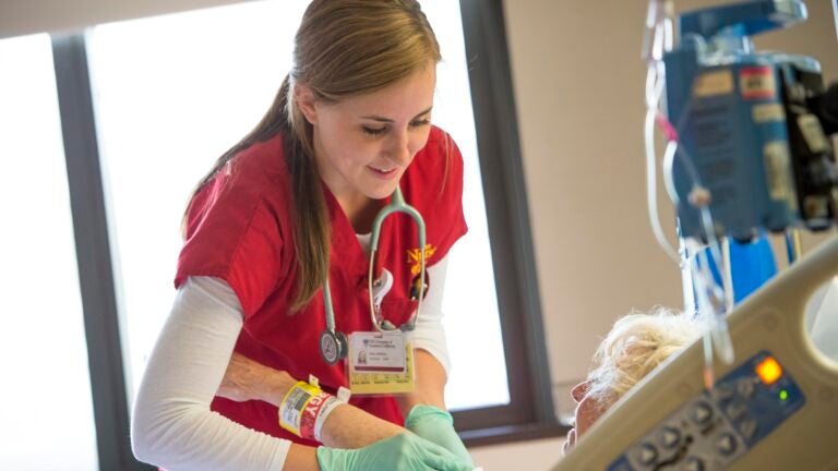 A Keck Medicine of USC nurse attends to an elderly patient in a hospital room.