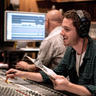 A student at a sound board directing music.