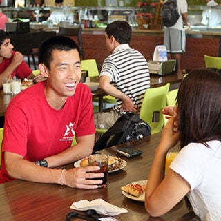 Students sitting at a table with plates in front of them.