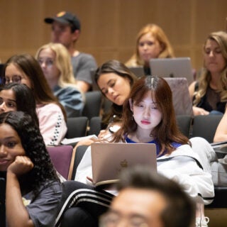 Students on laptops in a class in an auditorium at USC Annenberg.