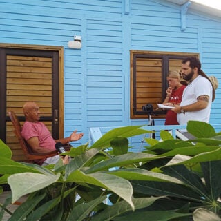 Two USC students interview a man outside his home for their research