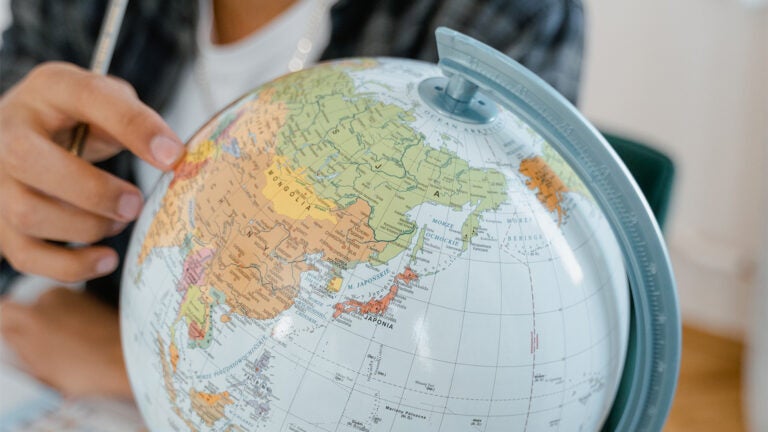 A person points to a world globe.