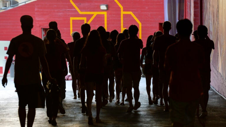 Silhouetted Trojans walk through the Coliseum tunnel, with the view of the SC logo painted on a red wall.