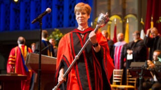 A USC faculty member carries the symbolic staff during New Student Convocation on campus.
