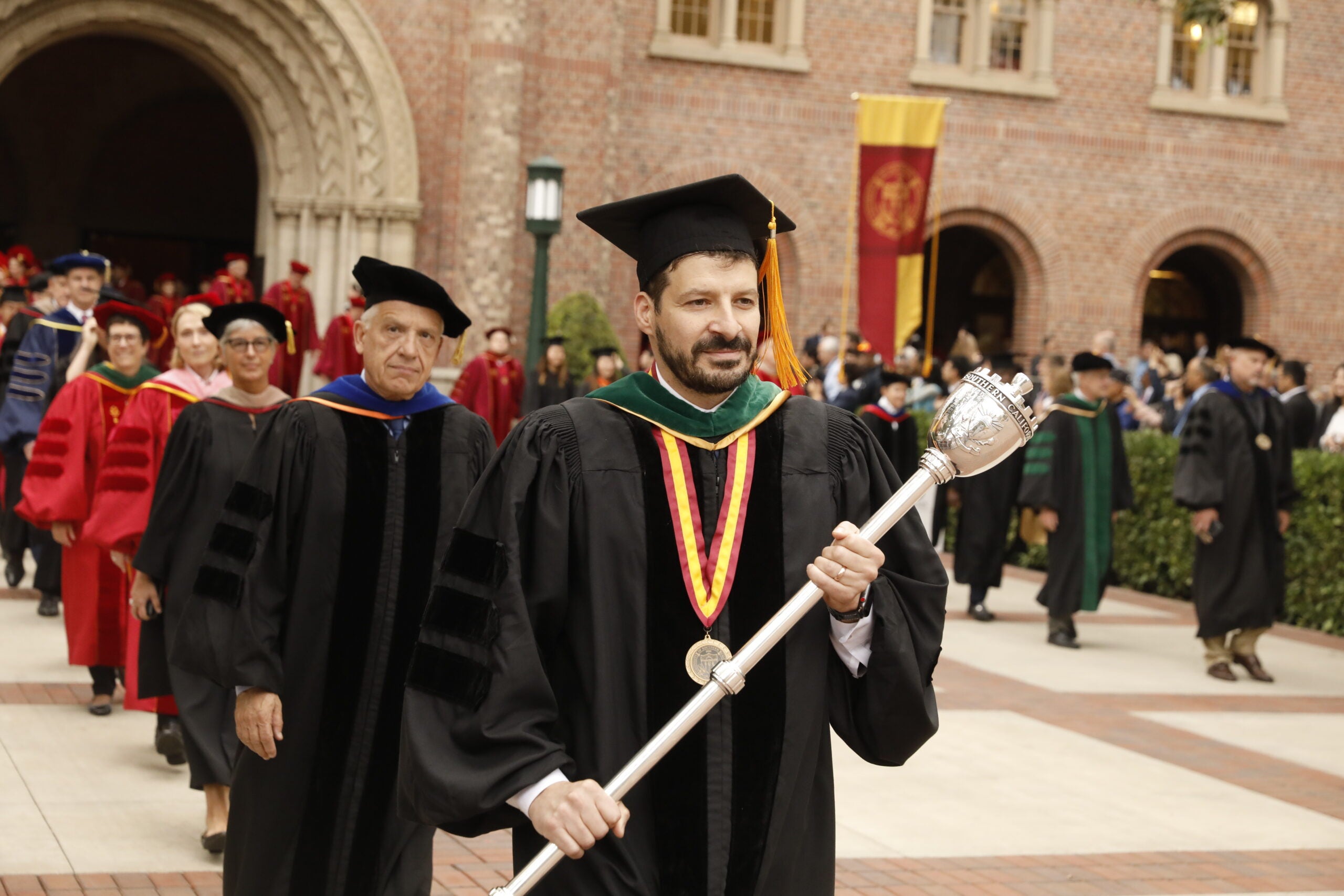 A graduating student carries a symbolic ceremonial item during USC's commencement exercises.