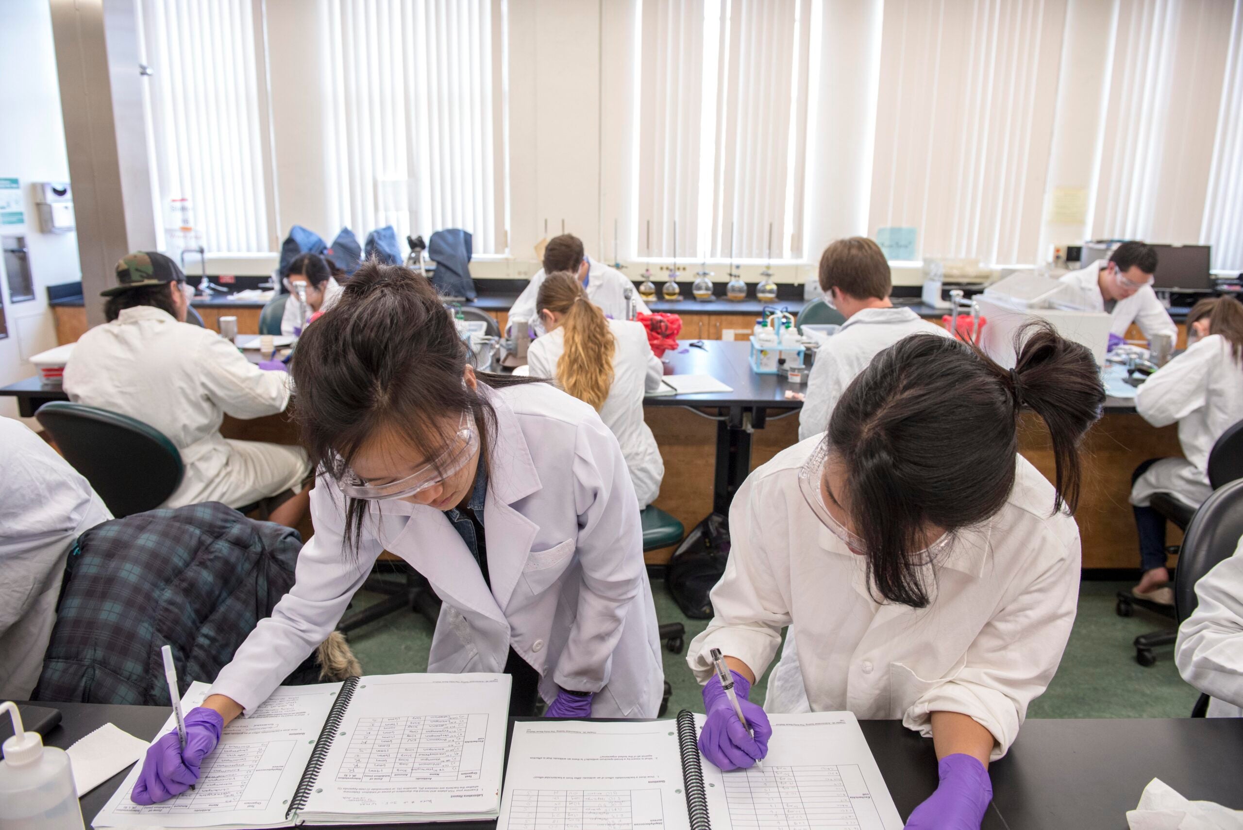 Students wearing scientific lab gear take notes during a class at USC.