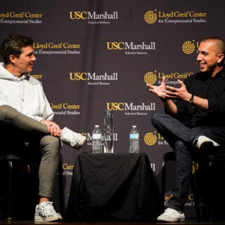 A student and guest speaker sit on a stage, holding a conversation.