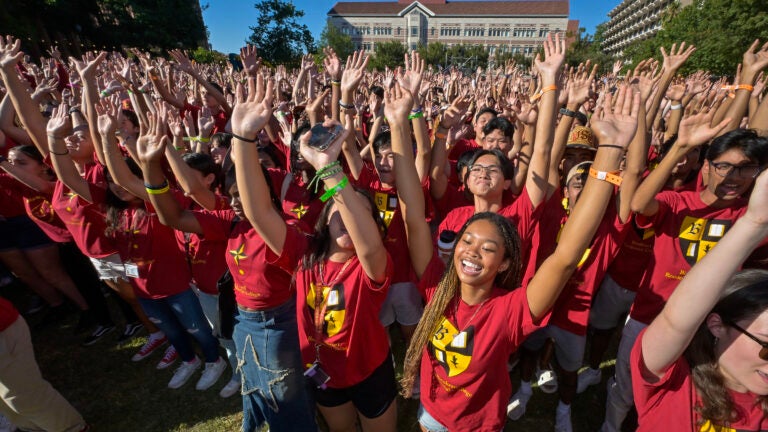 USC students with hands raised at a spirit rally