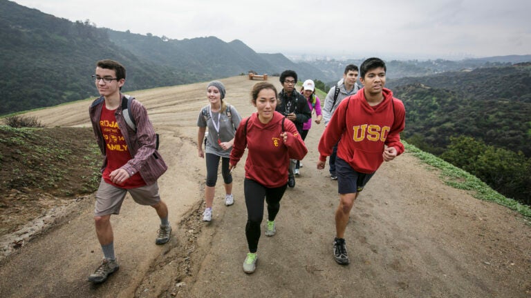 Five USC students hiking up a train by the Hollywood sign.