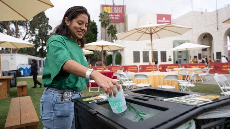 A student places something into a recycling bin at the LA Coliseum