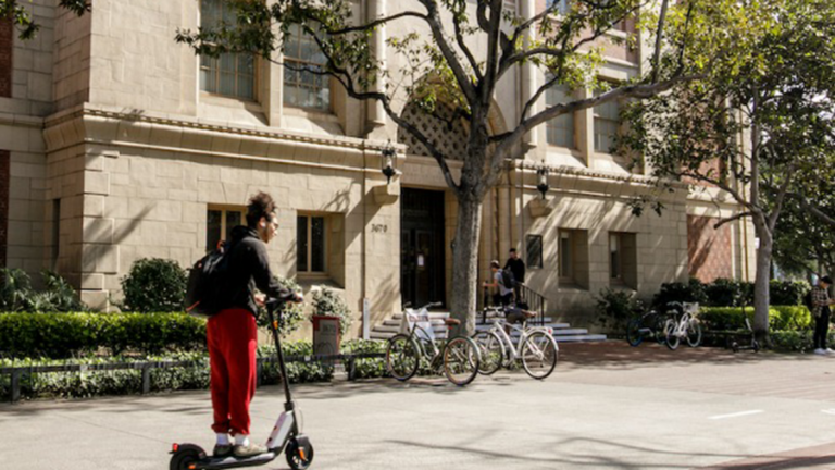 Student riding a scooter on campus