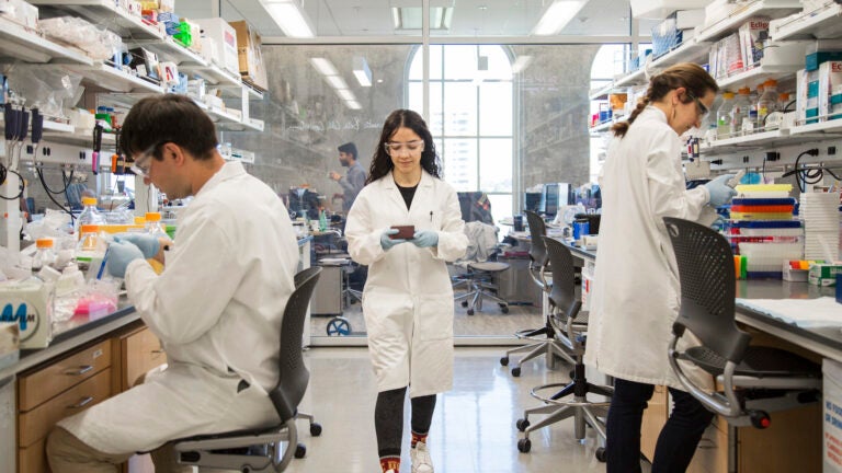 A USC researcher walks between two others inside USC Michelson