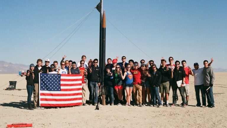 USC Rocket Propulsion Lab team hold an US flag in front of their rocket prior to launch