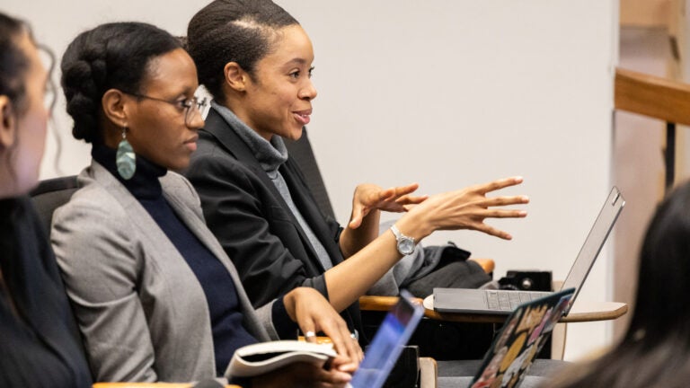 Two female students seated at a classroom responding to the speaker