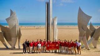 NROTC midshipmen and faculty pose on Omaha Beach