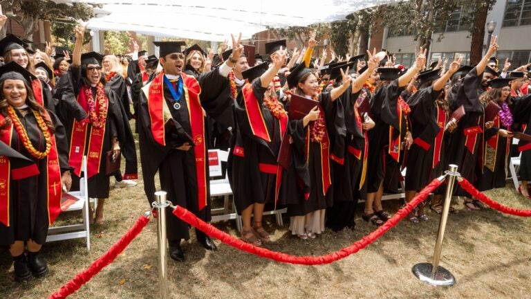 Graduates in caps and gowns celebrate during a USC Bovard College commencement ceremony.
